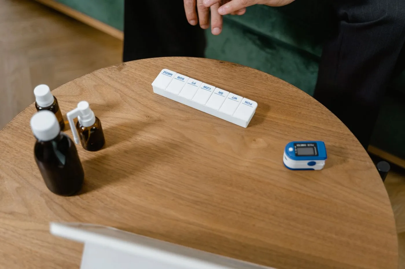A weekly pill organizer and medicine bottles on a warm wooden table.